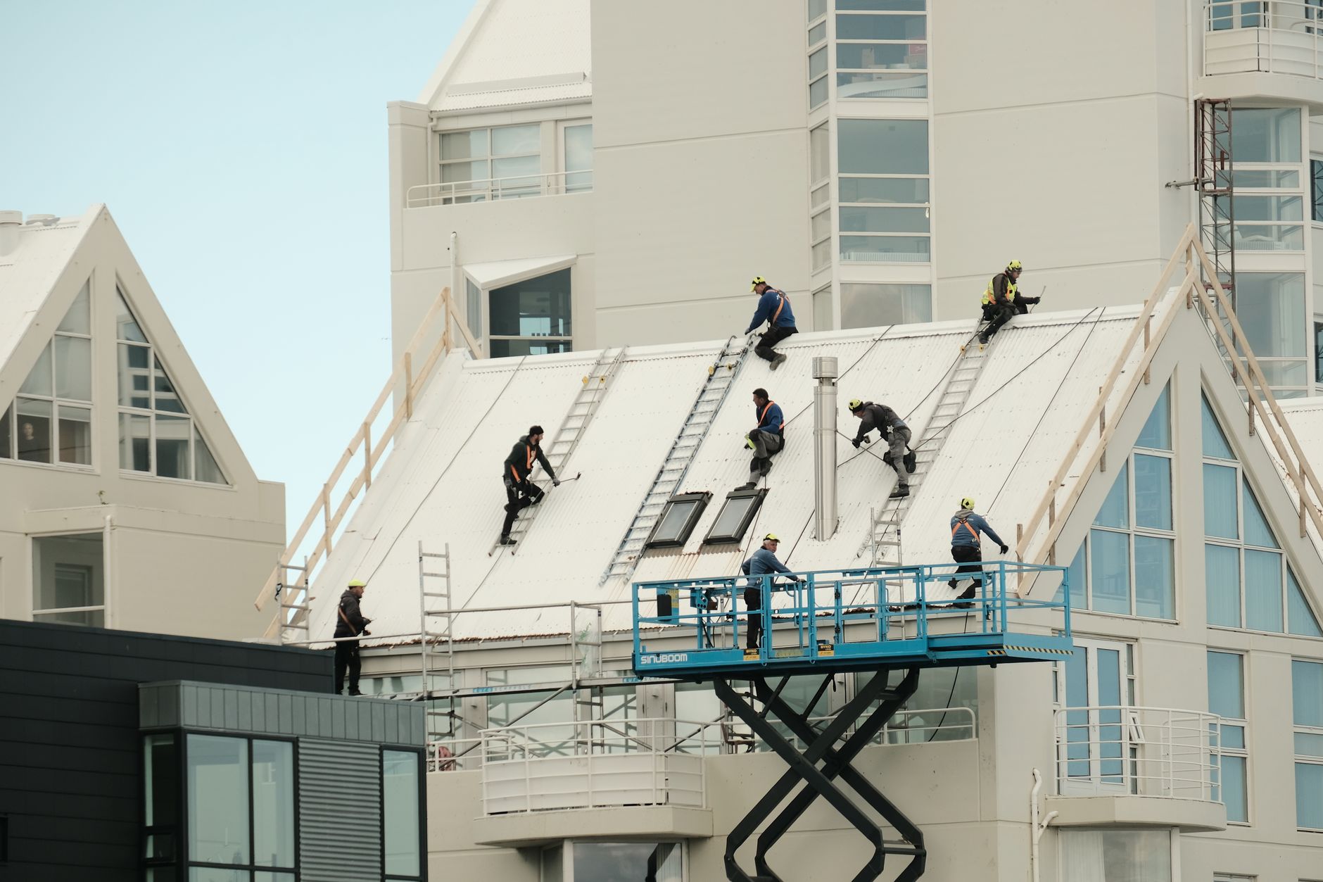 Construction workers repairing a modern roof, highlighting teamwork and safety.